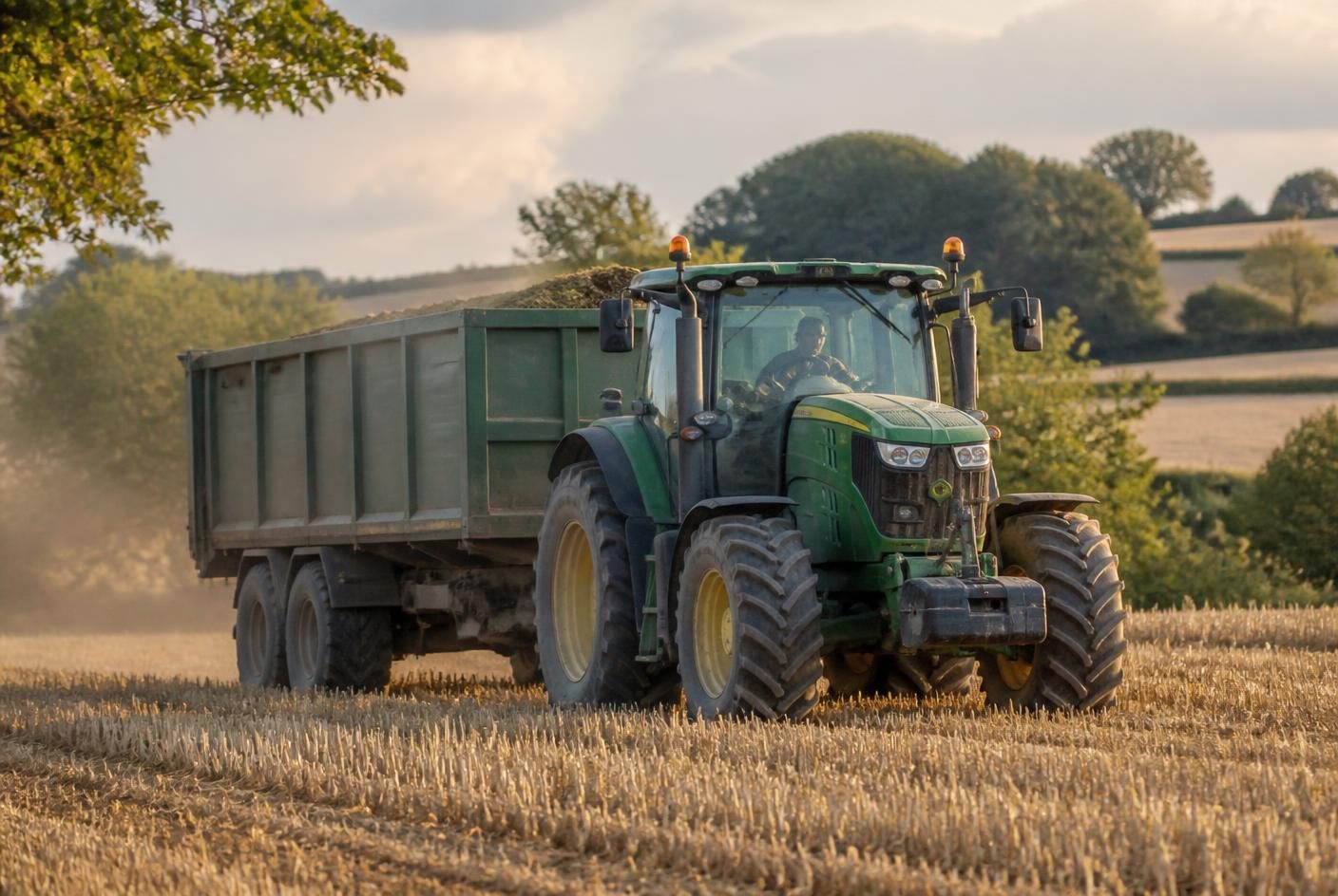 Tractor and trailer working a stubble field at harvest
